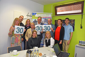 Personen halten Schild mit einer 30 in die Kamera.