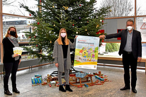Foto mit 3 Personen die das Titelbild des Familienpasses als Plakat halten