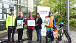 Personen stehen vor Fahrrädern und halten Plakate in der Hand.