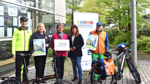 Personen stehen vor Fahrrädern und halten Plakate in der Hand.