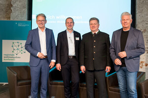 Gruppenfoto mit vier Männern stehend auf einer Bühne.