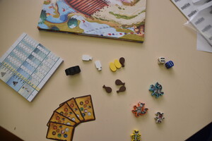 Brettspiel mit kleinen Figuren und Karten auf einem Tisch.