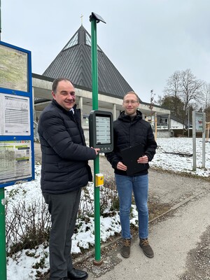 Zwei Personen testen digitale Fahrgastinformation an einer Bushaltestelle.