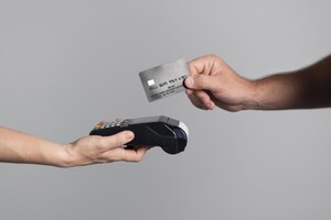 Hand hält Debitkarte an Kartenlesegerät.