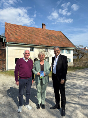 Drei Personen mit Flyer stehen vor Jexhof-Gebäude.