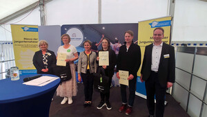 Gewinner stehen mit Urkunden am Messestand der Wirtschaftsförderung.