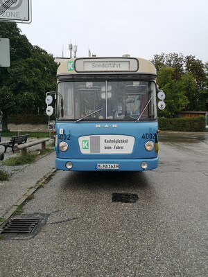 Historischer blauer Bus steht auf Parkplatz.