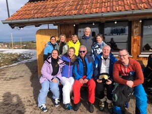 Skifahrer sitzen vor einer Hütte.
