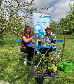 Zwei Frauen sitzen im garten an einem runden Tisch.