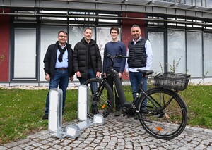 Vier Männer stehen hinter einer neuen grauen Fahradabstellanlage.
